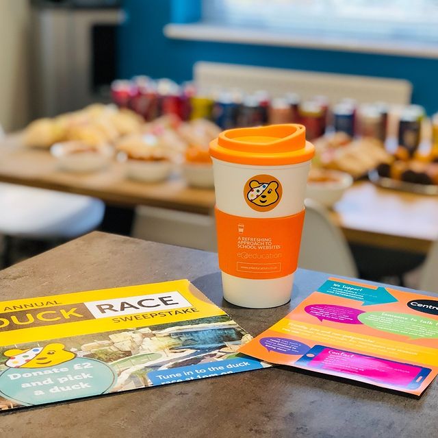 A selection of sweet treats on a table with a Pudsey sticker on a coffee mug in the foreground