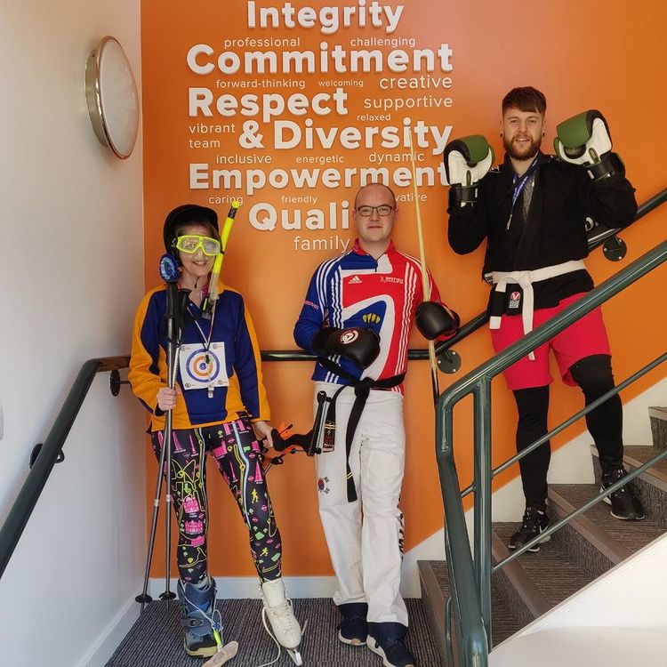 3 members of staff on the stairs in various sporting gear for charity